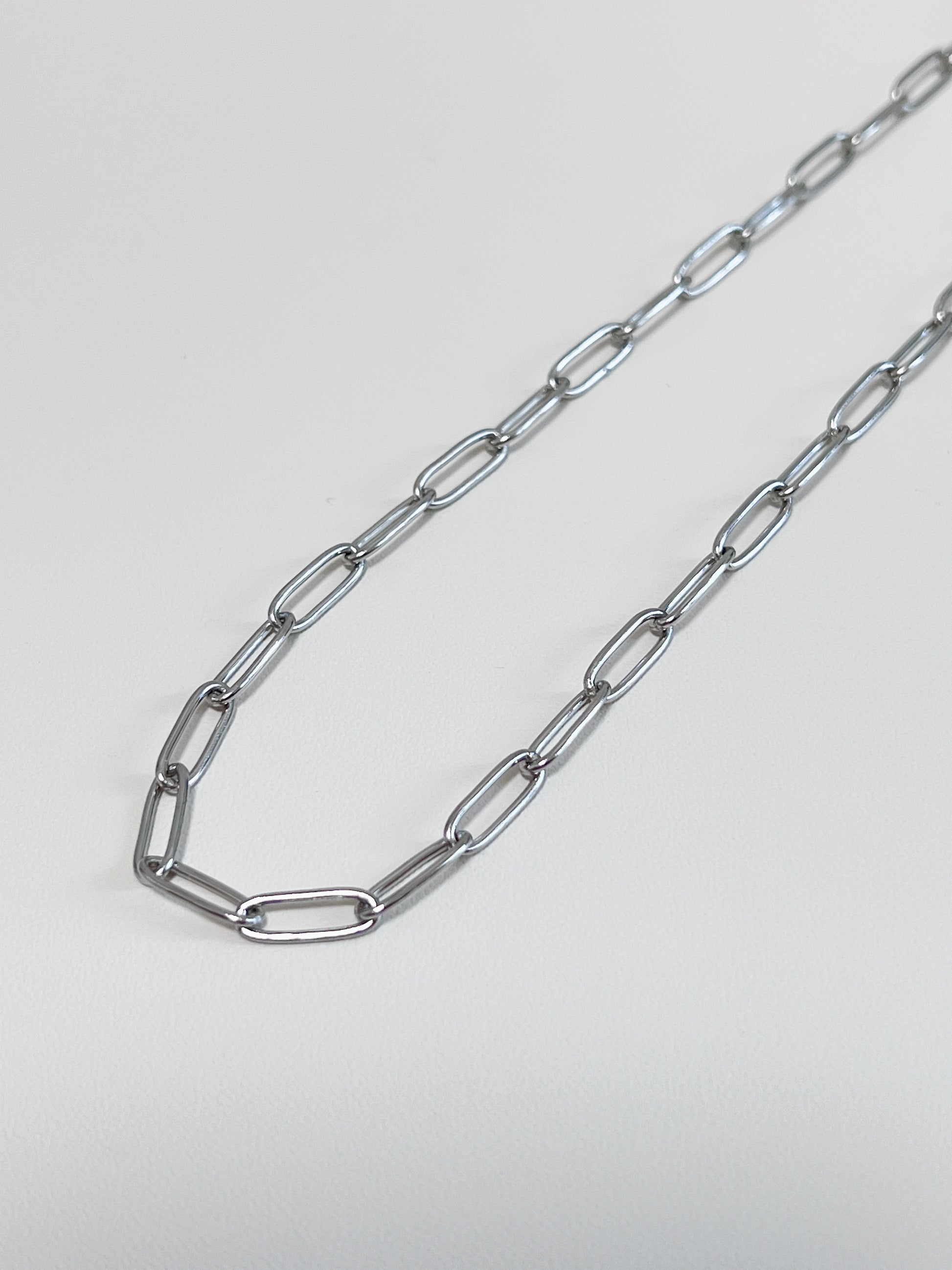 Still life presentation highlighting the supple fabric-like drape of a contemporary luxury paperclip collar chain