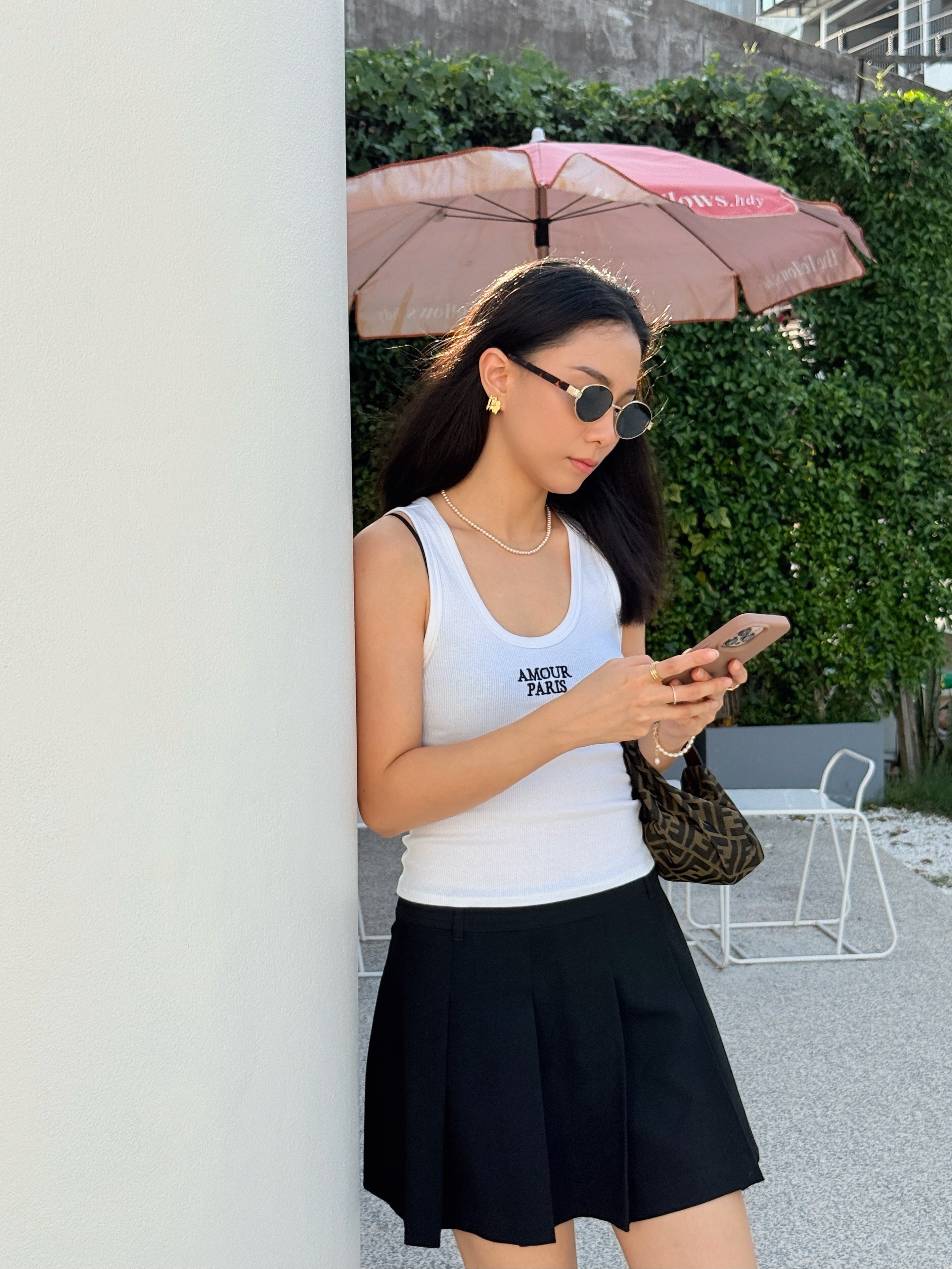 Woman styling pearl jewellery and gold statement piecees effortlessly for her summer city escape 