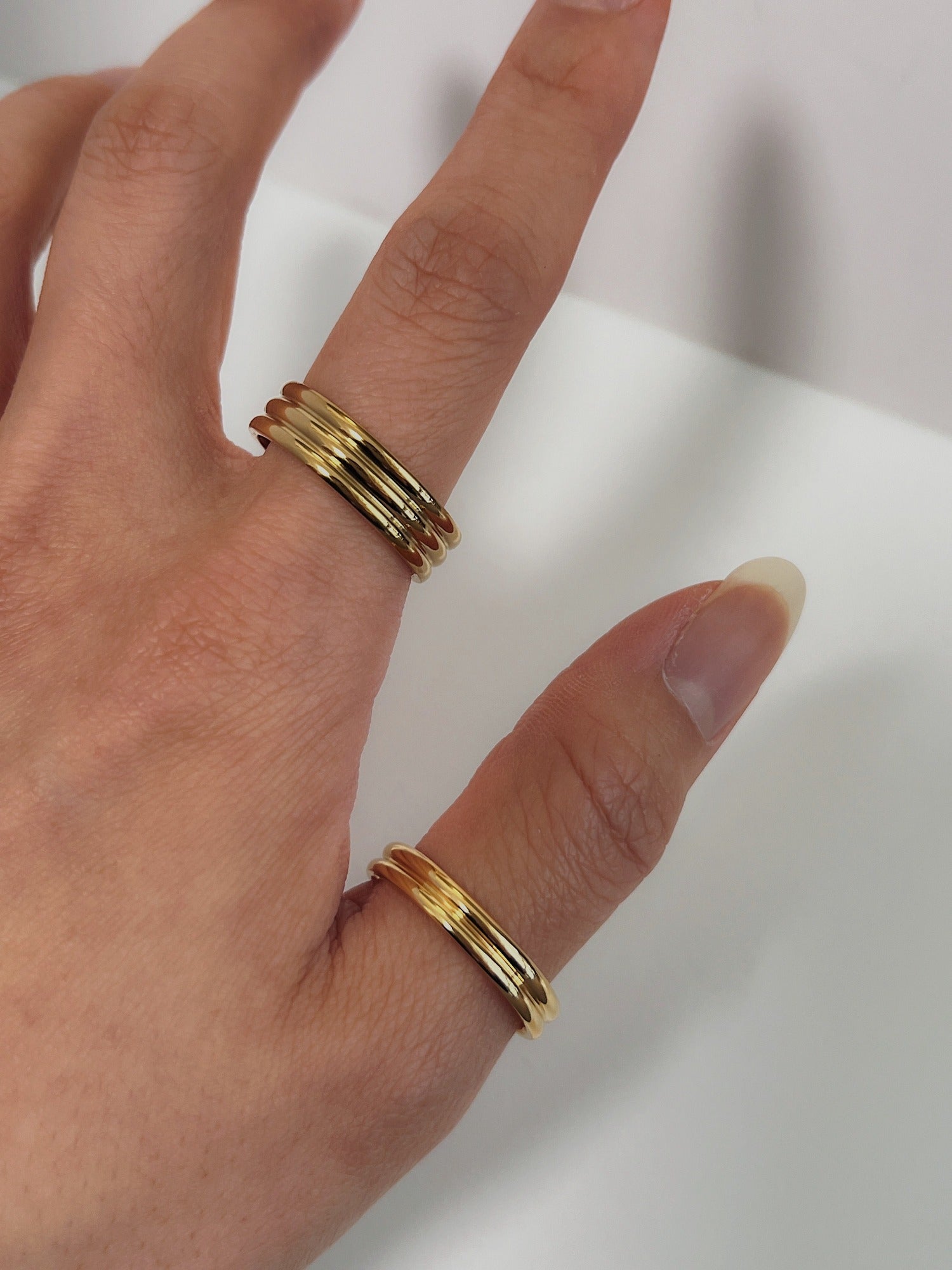 Luxe stack of slim and thick gold ribbed rings on a hand model