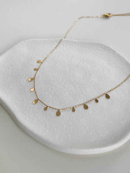 Close up view of high polish summer gold PVD organic pendant resting on fine steel link chain