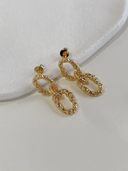 Close up perspective highlighting the crumpled textured hammered finish of 18k gold pvd drop earrings