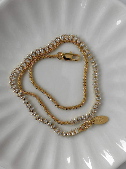 Thea asymmetric marquise choker necklace showcasing half crystal half gold chain layout flat lay
