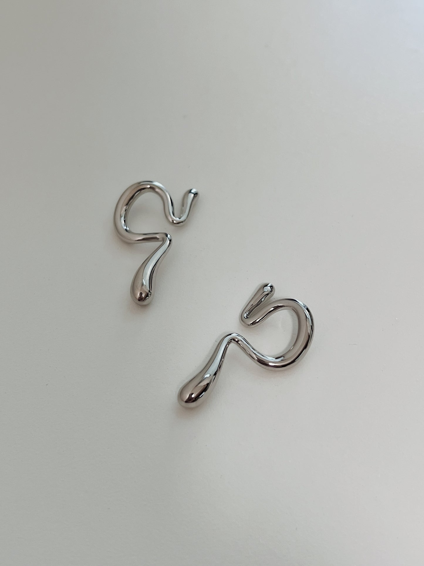 Close-up of the fluid, wave-like silhouette on a waterproof silver ear wrap.
