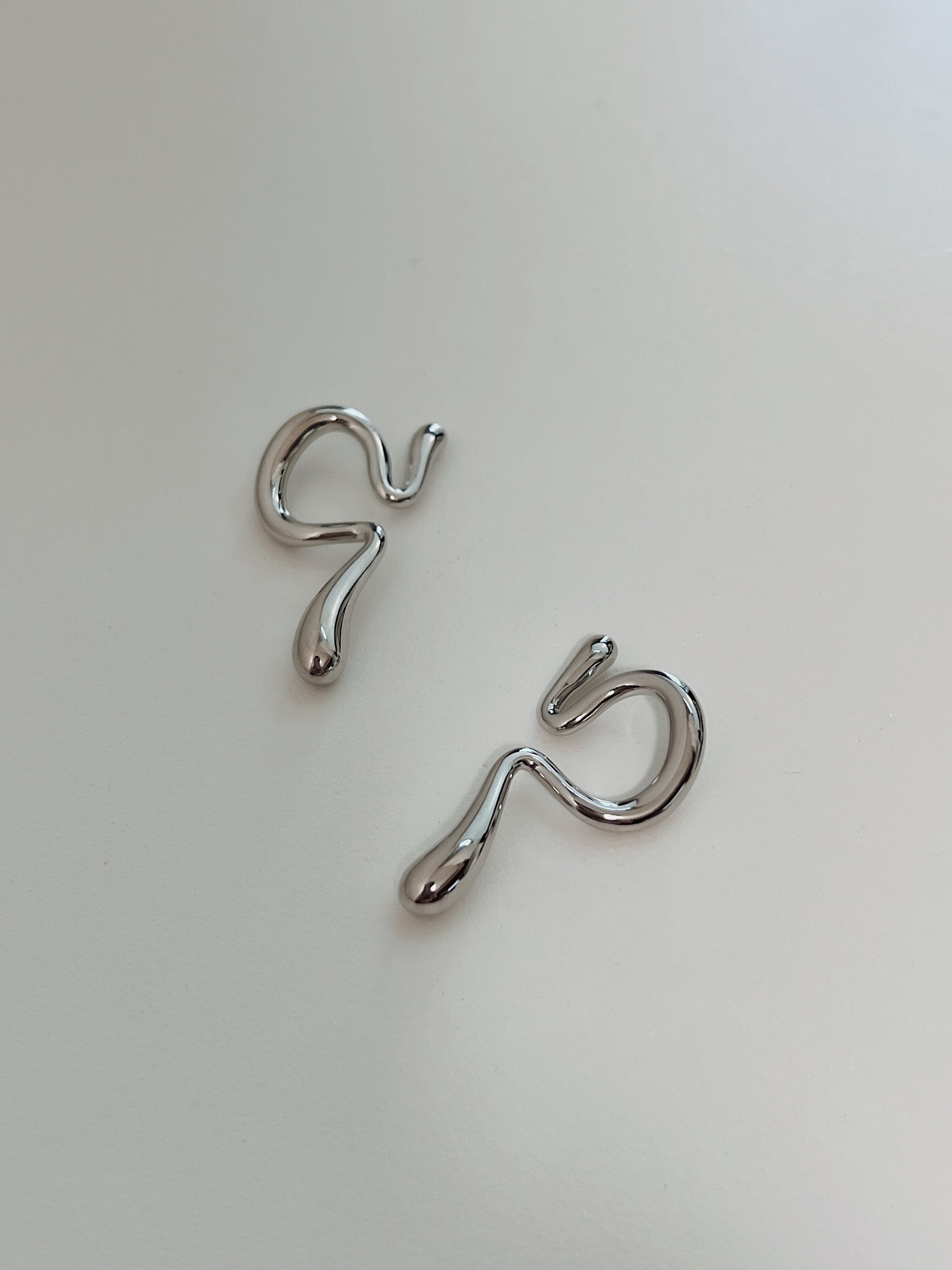Close-up of the fluid, wave-like silhouette on a waterproof silver ear wrap.