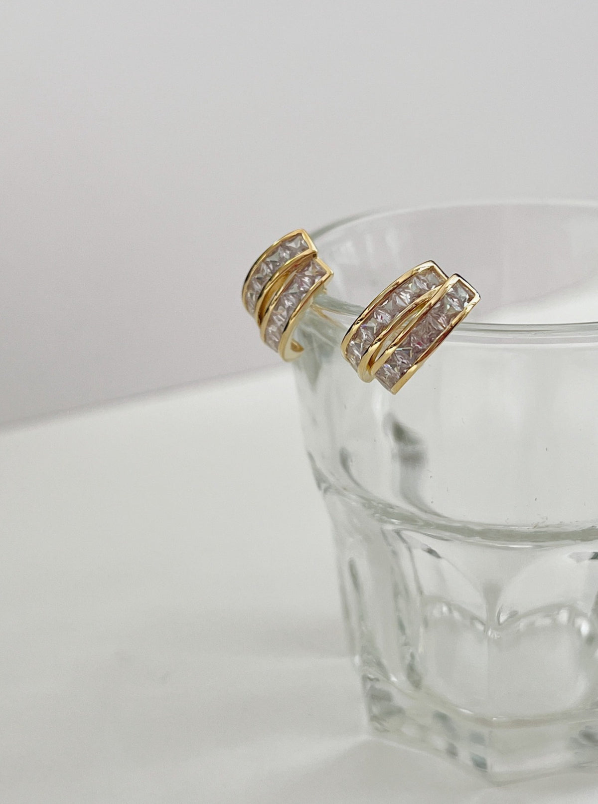 Light reflection on polished gold dual rails and princess cut cubic zirconia of Tiana clip-on earring
