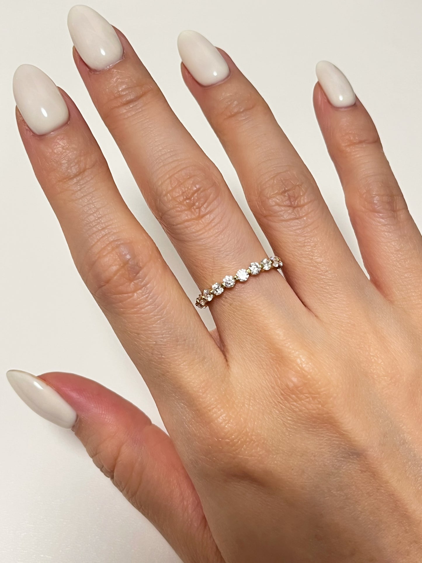 The Callie gold eternity band showing its continuous line of sparkling stones from a top angle on a clean white countertop