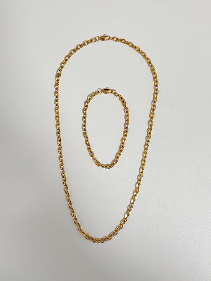 Studio layout displaying the Trixie cable chain bracelet nestled perfectly inside its matching luxury gold link necklace on a seamless white surface.