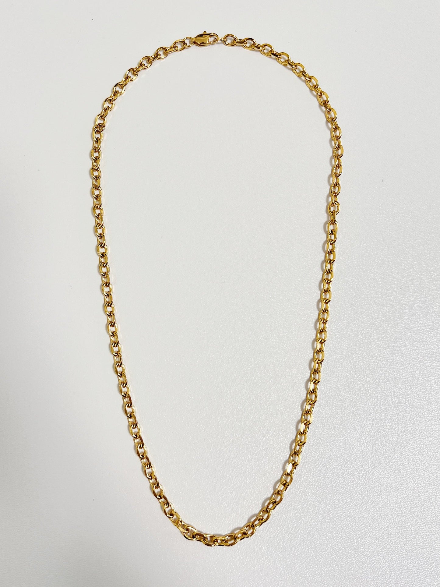 Studio flat lay of the Trixie cable chain necklace displaying its uniform round link pattern on a crisp white backdrop