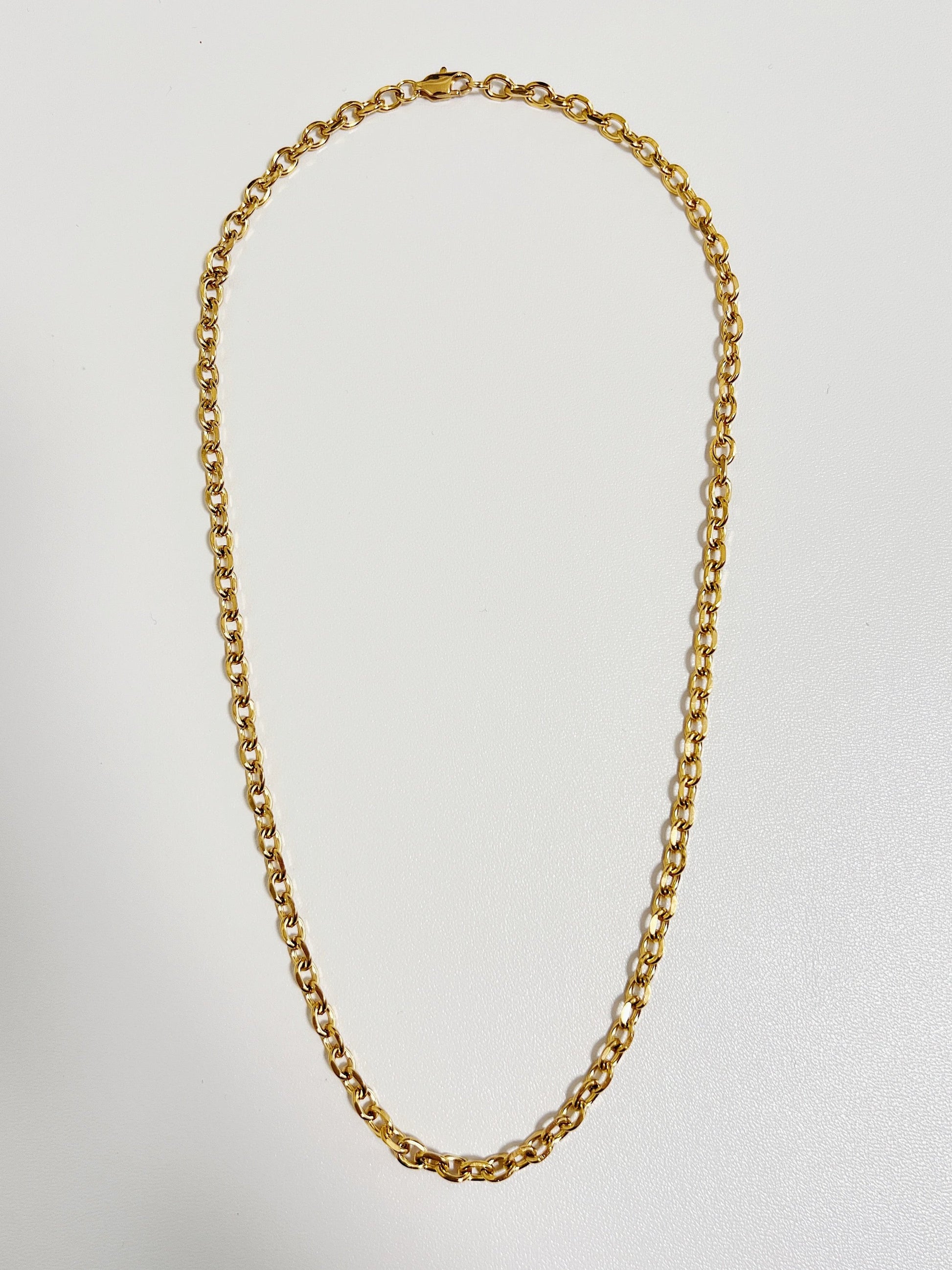 Studio flat lay of the Trixie cable chain necklace displaying its uniform round link pattern on a crisp white backdrop