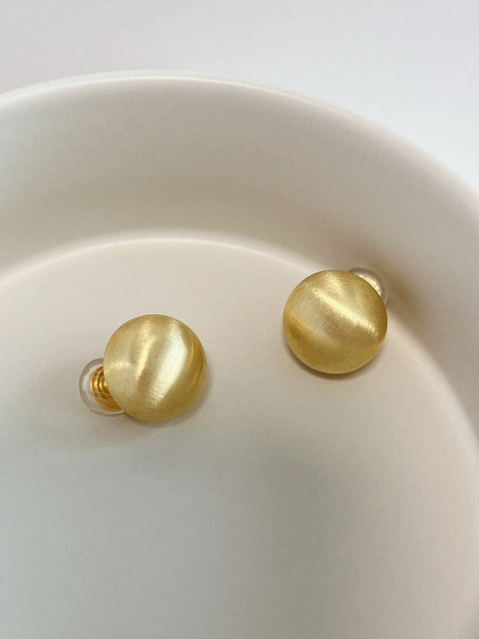 Pair of 16K gold plated Tyla brushed dome clip-on earrings on ceramic plate