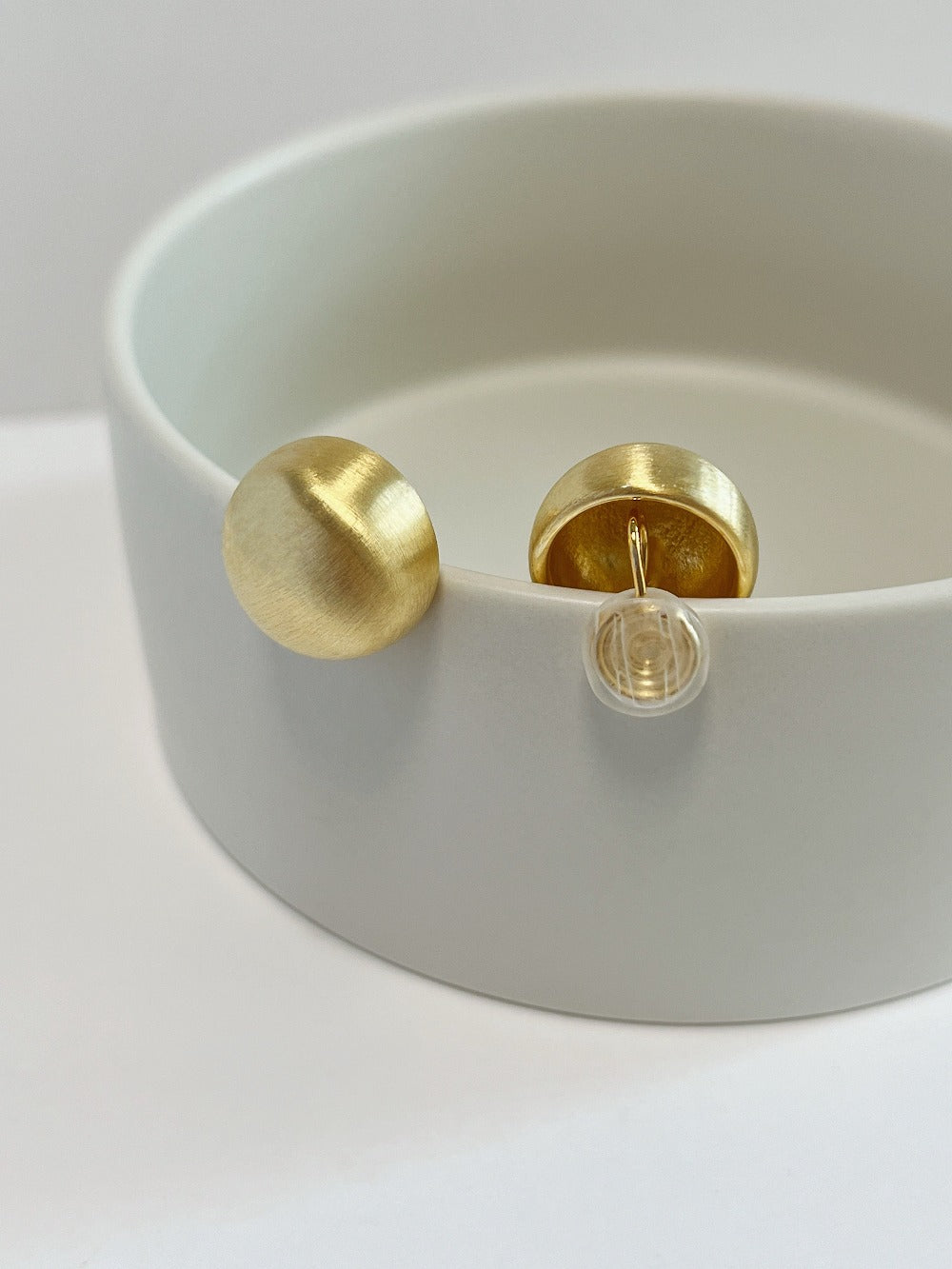 Macro view of hand-brushed satin matte gold surface detail on 18mm Tyla dome clip-on earring
