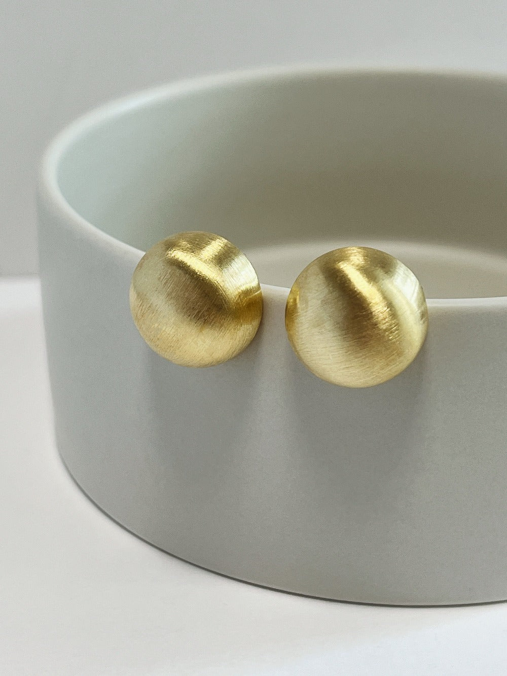 Pair of gold plated Tyla brushed dome clip-on earrings showing satin texture