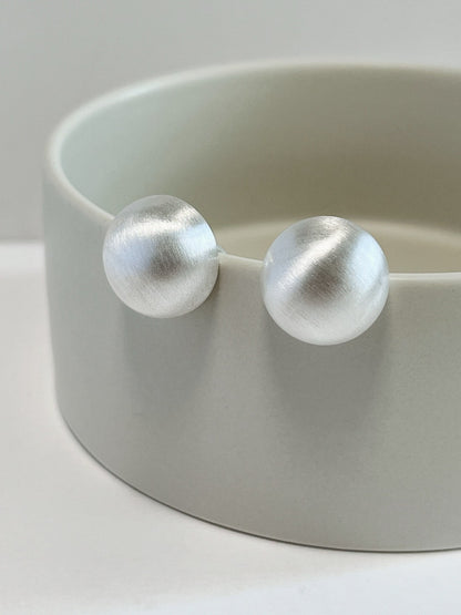 Pair of rhodium plated silver Tyla brushed dome clip-on earrings showing satin texture
