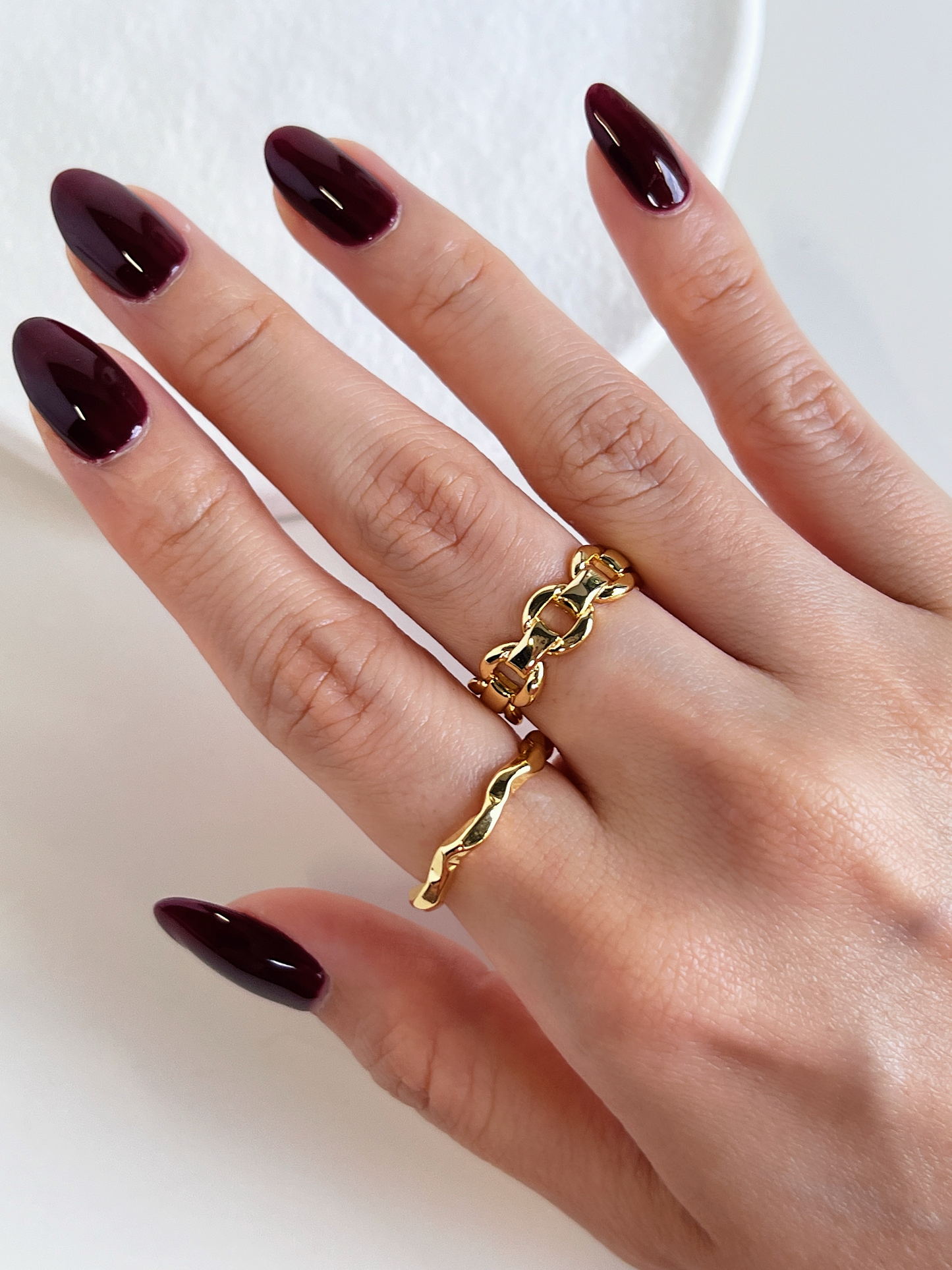 High-mirror gold sculptural chain ring catching light on model's hand