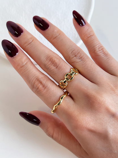 High-mirror gold sculptural chain ring catching light on model's hand