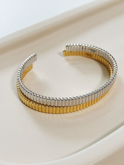 Studio overview showcasing the Vede ribbed flexi cuff stacking bangle set in both 18K gold vermeil and silver stacked close together on a cream ceramic tray.