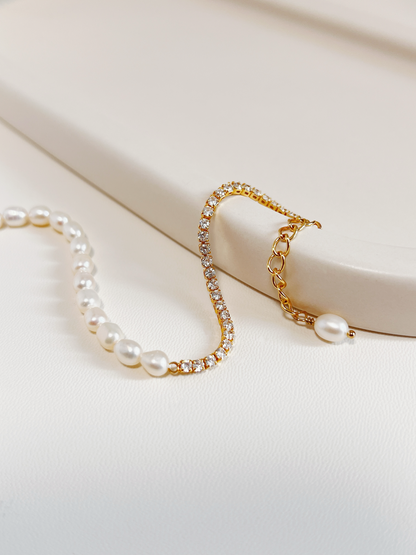 Macro close-up of the gold Vera bracelet curved gracefully over a textured minimalist cream ceramic display tray, showing the continuous high-brilliance micro-set 5A cubic zirconia stones.