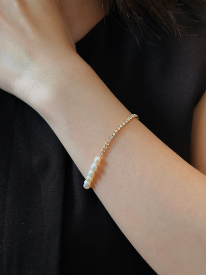 Editorial model shot showcasing the 5A cubic zirconia tennis side of the Vera gold bracelet against a black clothing backdrop, emphasizing a classic minimalist look.