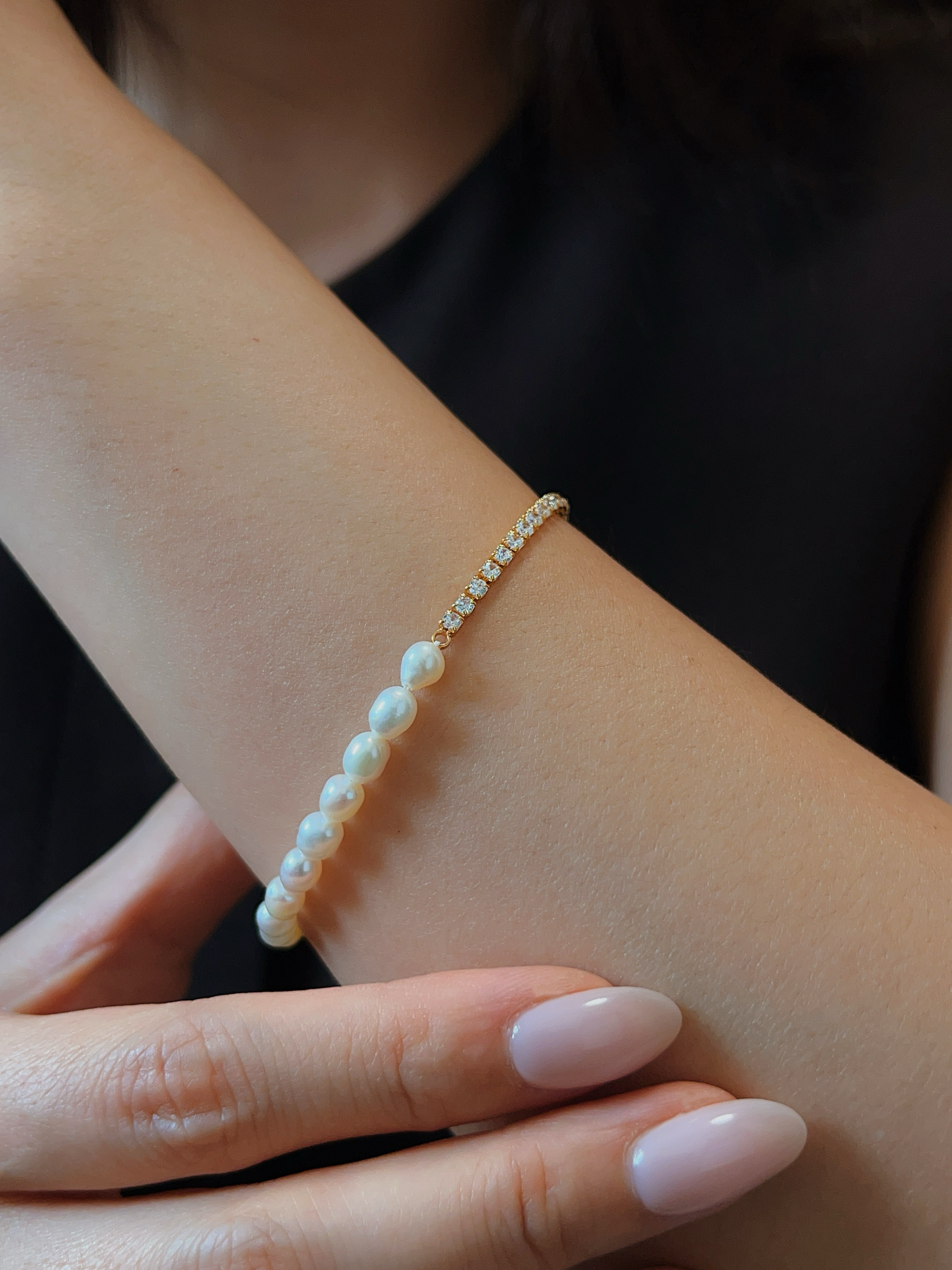 Close-up styling vignette of a model wearing the Vera asymmetric pearl bracelet, highlighting the exact point where the shimmering tennis chain transitions into organic pearls.