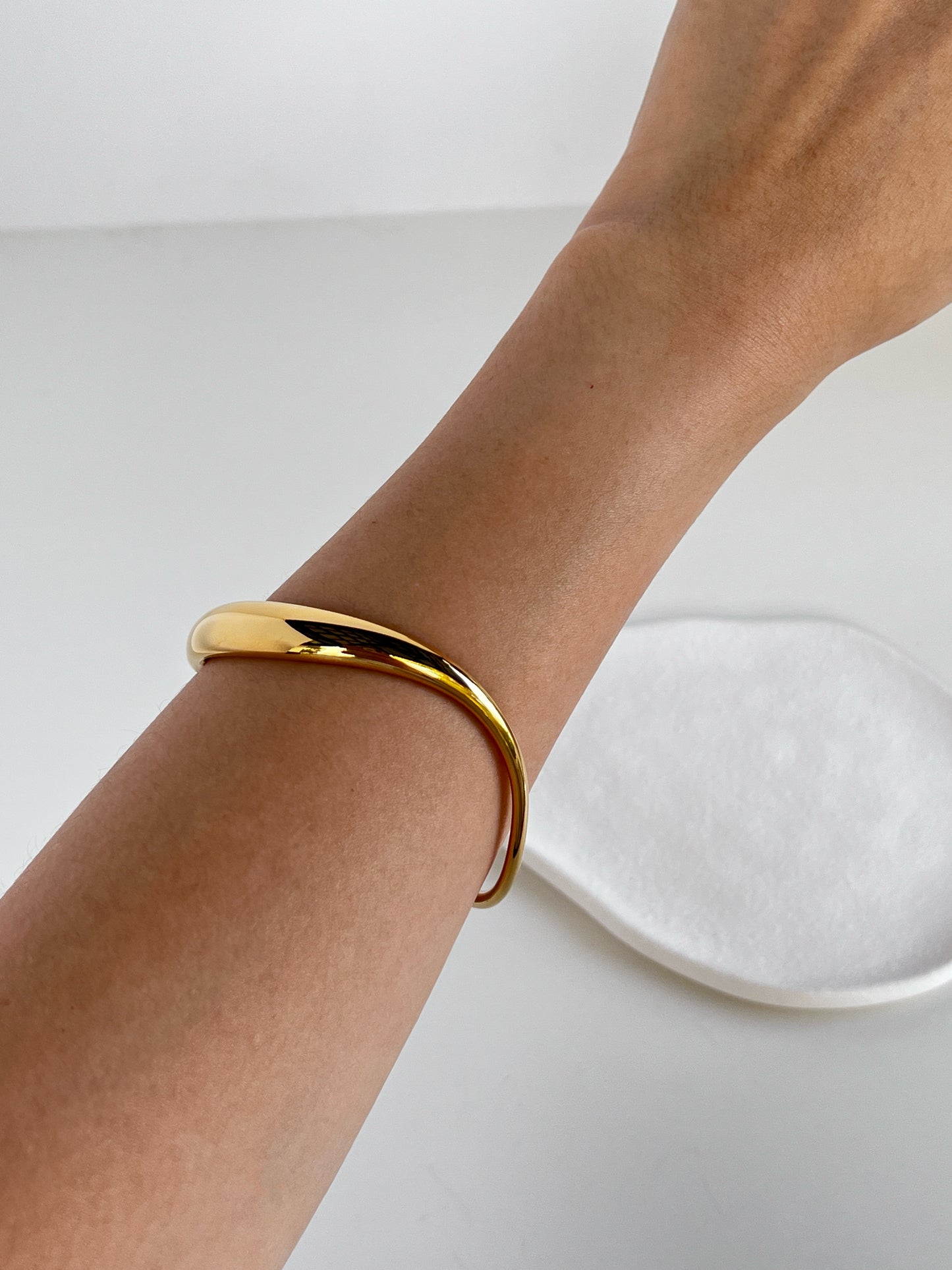 Wrist-shot of a model accessorized with the Vicky gold sculpted cuff.