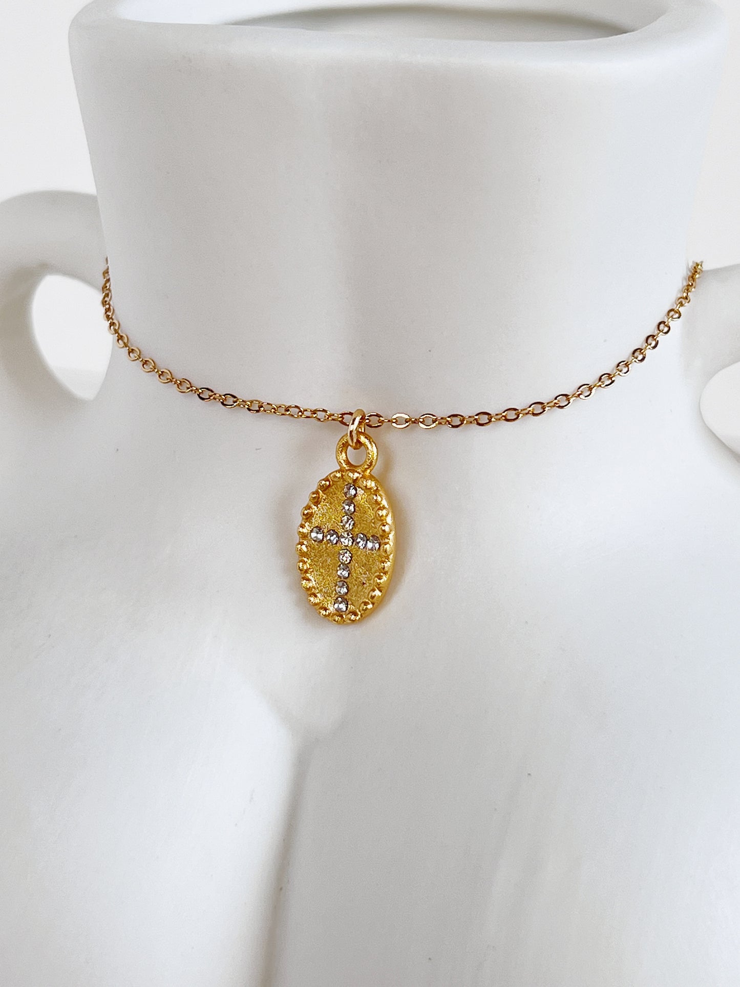 Detailed macro shot of the vintage beaded border and textured gold center of the Gianna medallion necklace resting on a white ceramic body sculpture