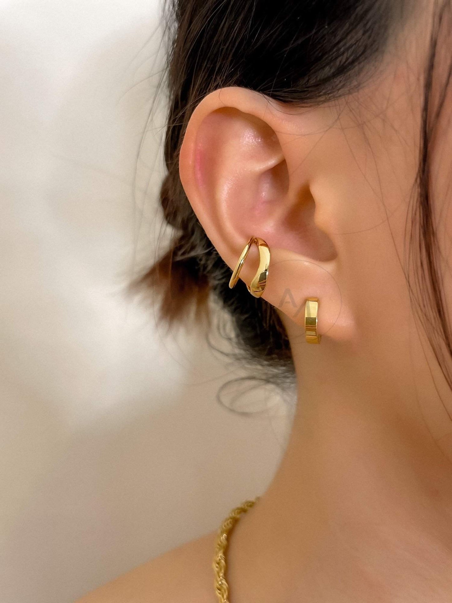 Lifestyle shot of a model styling the Beverly cuff with a minimalist gold stack.