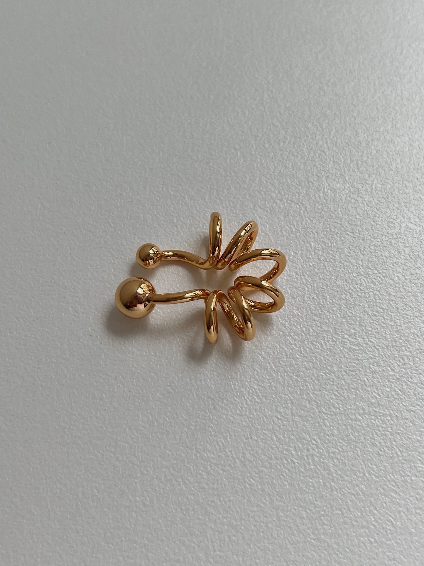 Side view showing the tubular spiral design of the 18K gold PVD cuff.