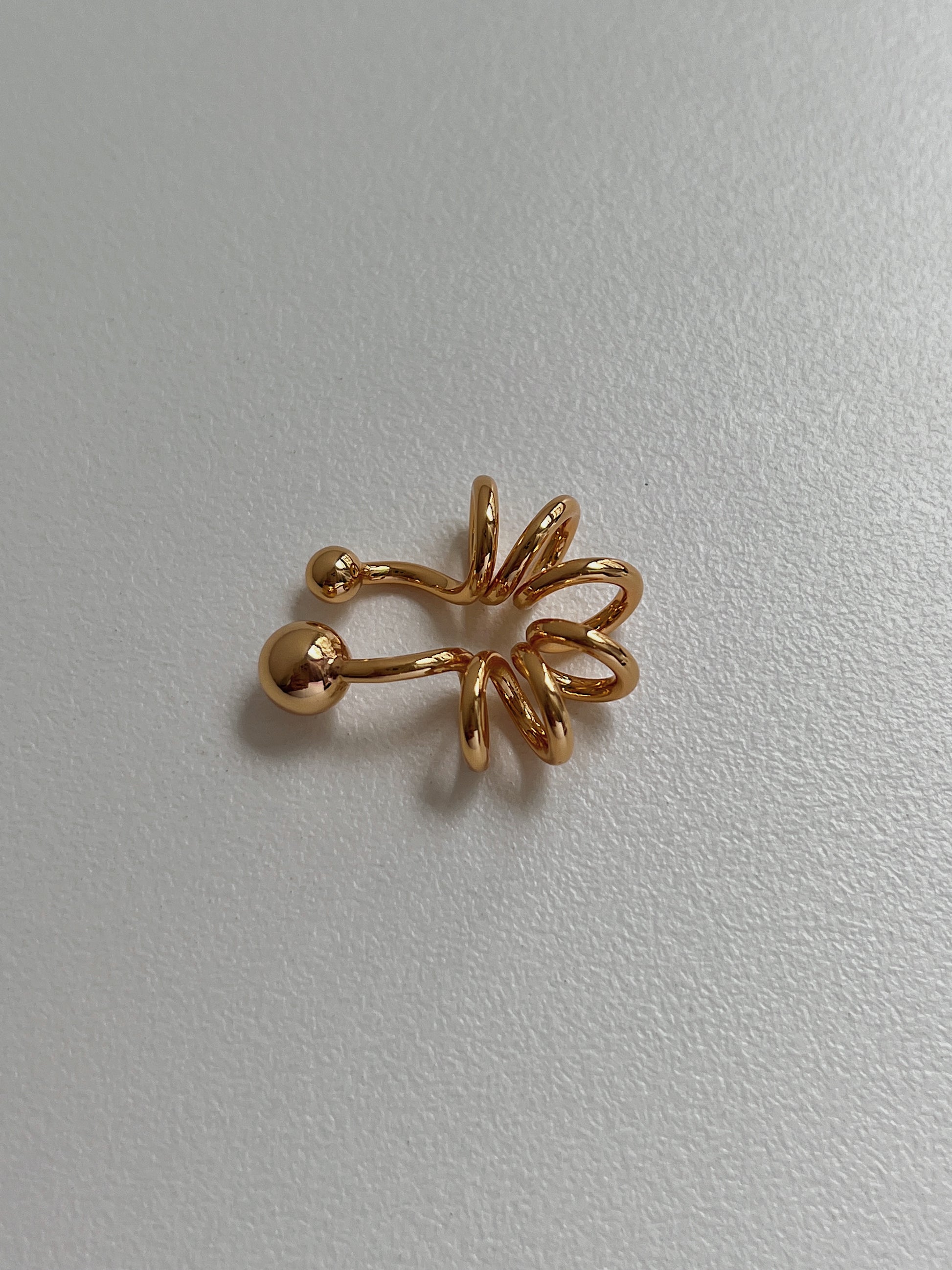 Side view showing the tubular spiral design of the 18K gold PVD cuff.