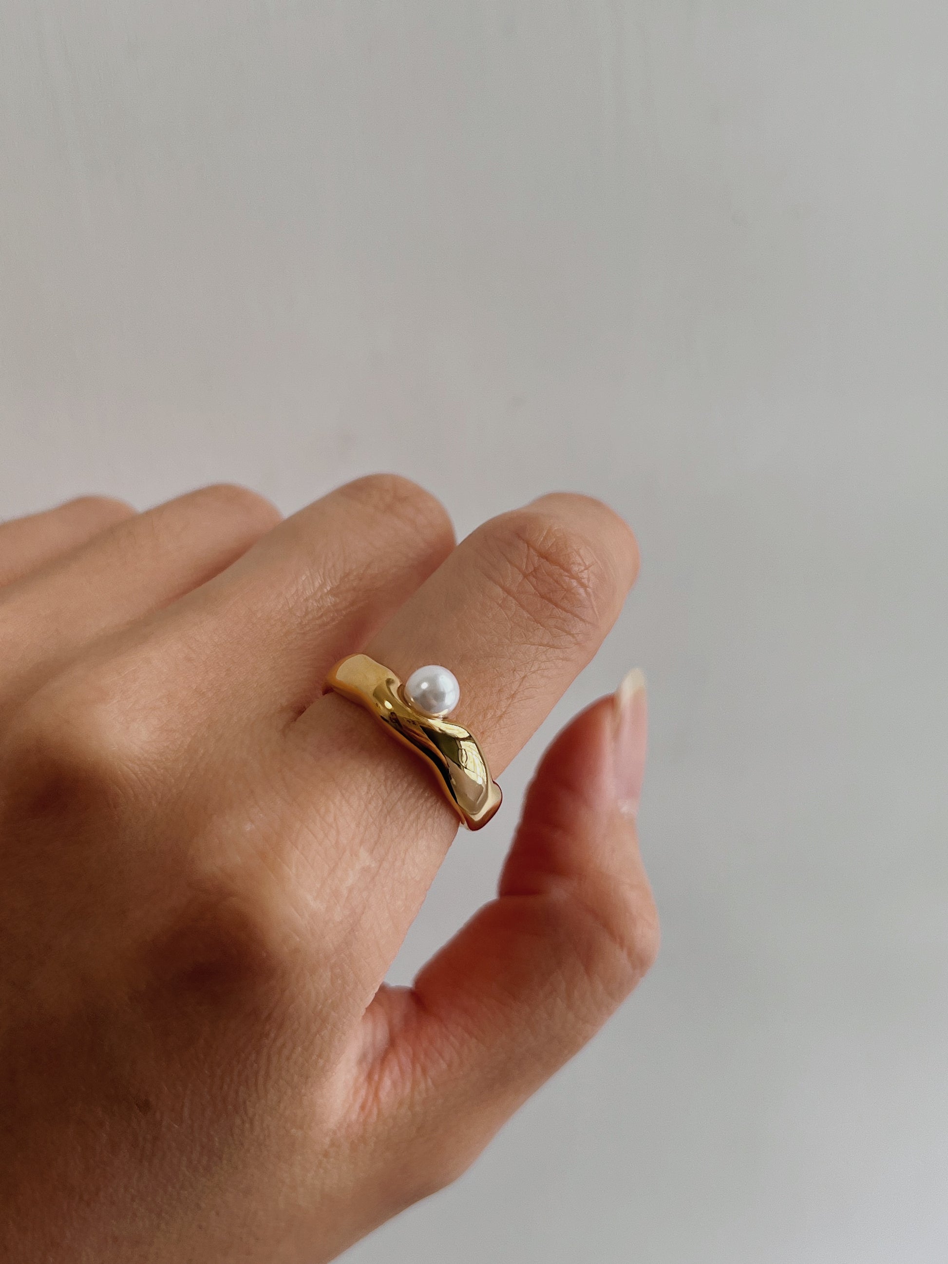 Close up of a model hand showing the comfortable fit of an organic pearl band.