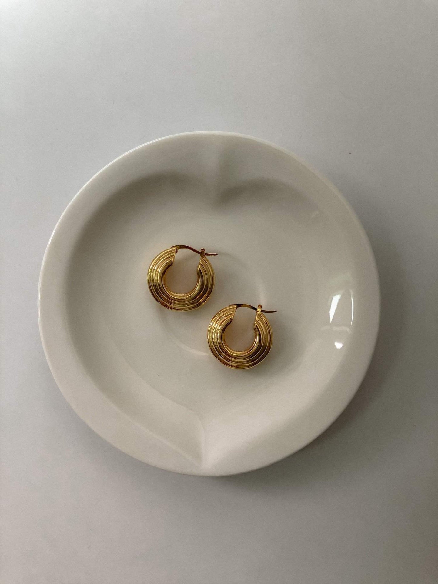 Elegant gold hoop earrings on white plate, perfect for everyday wear and special occasions