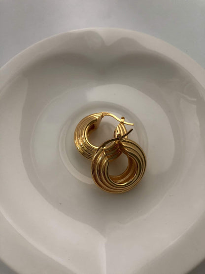 Minimalist gold hoop earrings displayed on a white plate, ideal for gifting and daily use