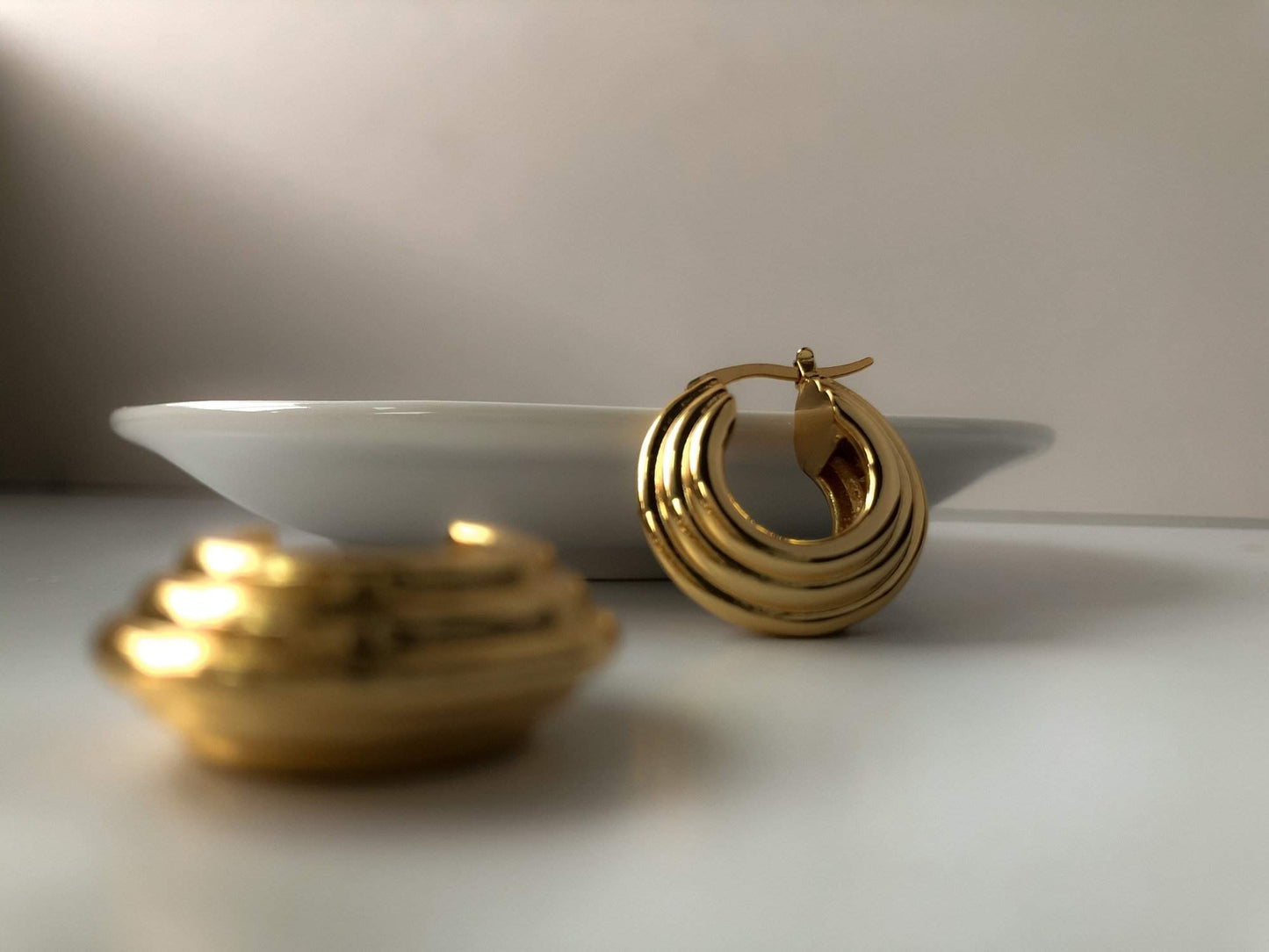 Minimalist gold hoop earrings displayed on a white plate, ideal for gifting and daily use