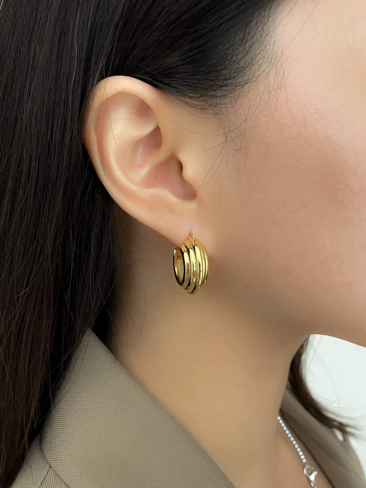 Classic gold hoop earrings on woman's ear, versatile accessory for any wardrobe