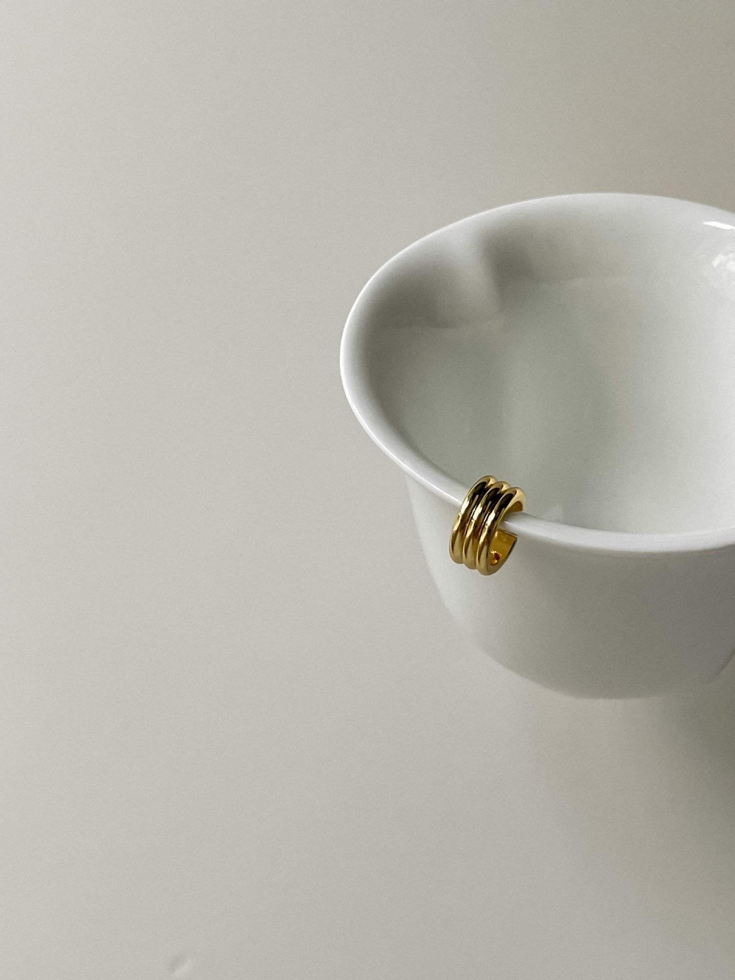 Sculptural triple-tier gold ear wrap for unpierced ears showcasing ribbed texture.