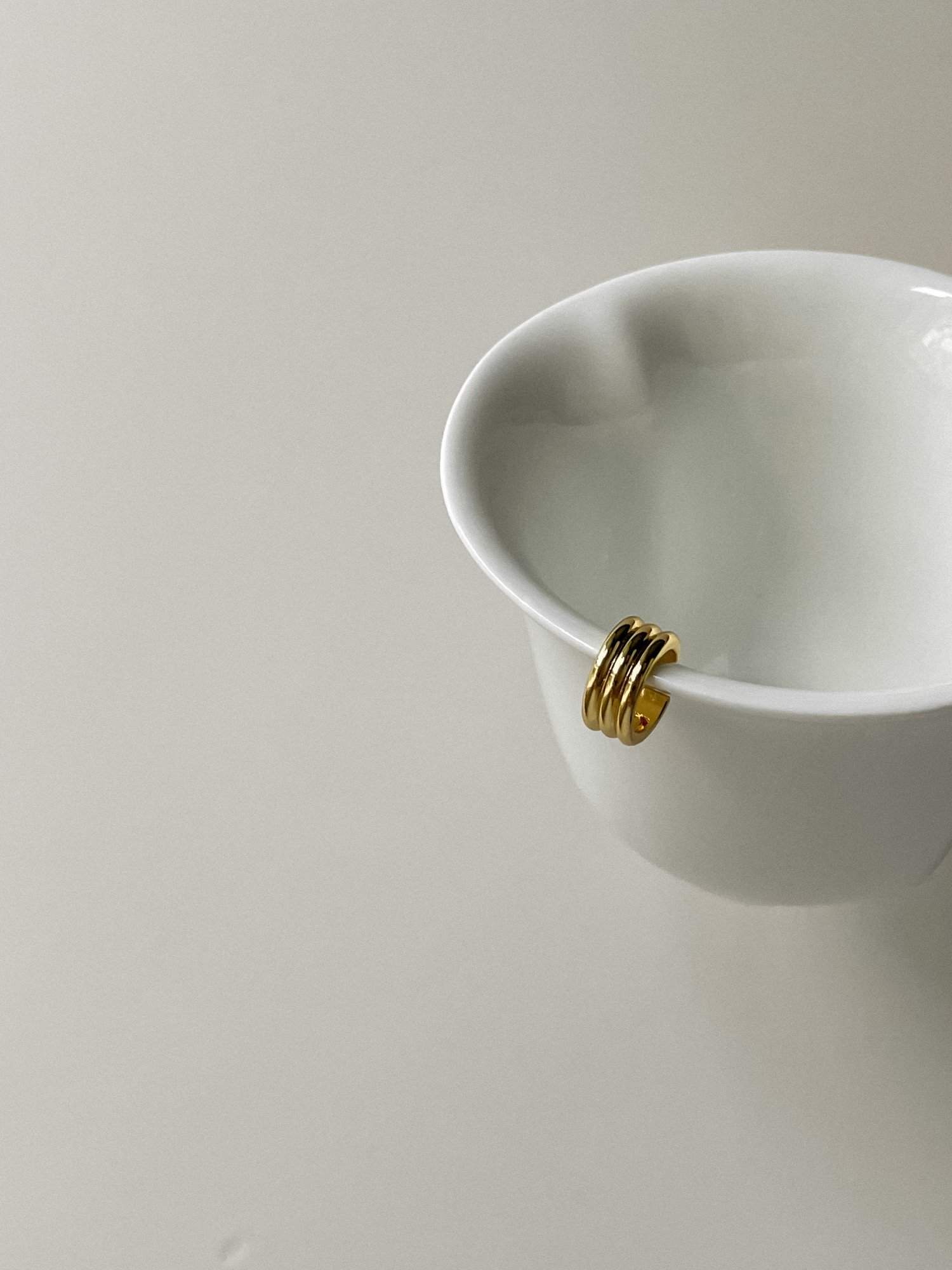 Sculptural triple-tier gold ear wrap for unpierced ears showcasing ribbed texture.