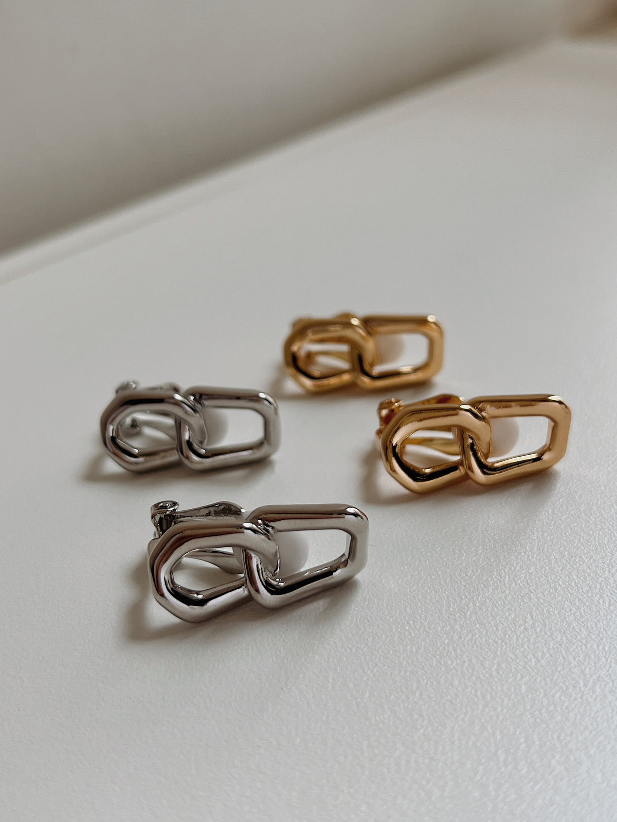 Close-up detail of the hinged lever clip mechanism fitted with a white non-slip silicone sleeve cushion on a non-pierced gold link earring.