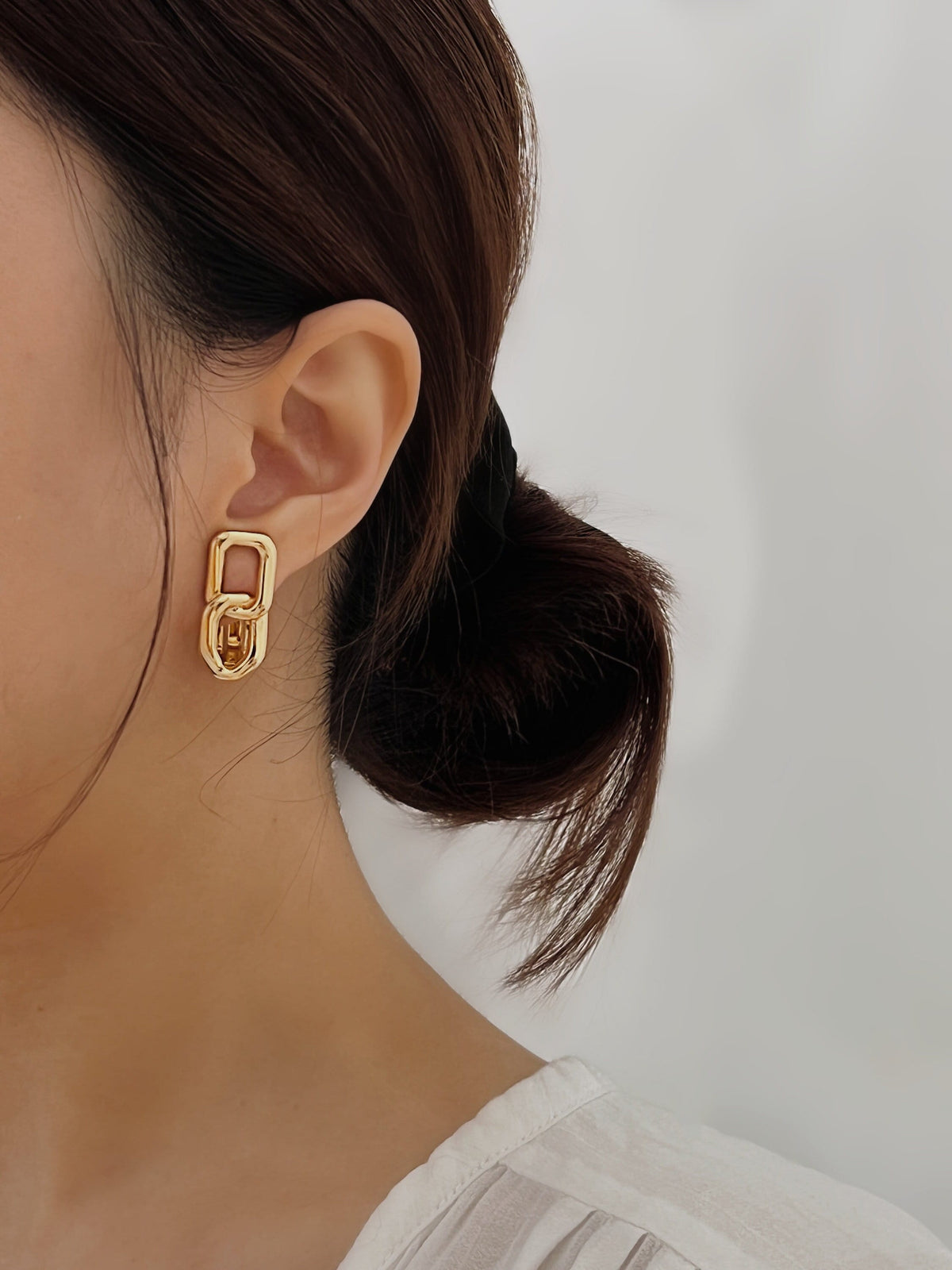 On-ear close-up showing the 40mm drop length and comfortable earlobe fit of the Aiden gold link clip-on earring.