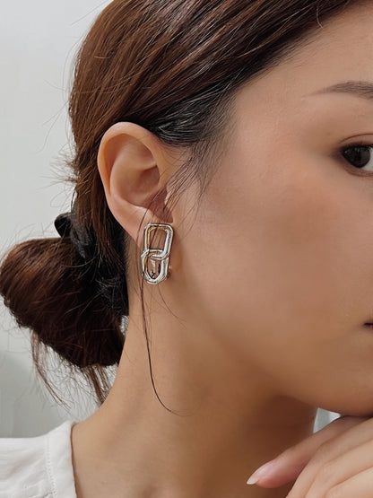 Natural daylight reflecting off the high-shine rhodium plated surface of a dual-link clip-on drop earring worn by model.