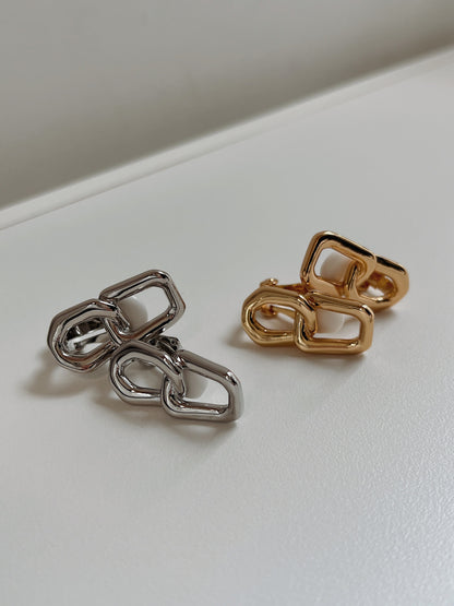 Overhead view comparing the 40mm by 13mm scale of gold and silver interlocking rectangular link clip-on earrings.