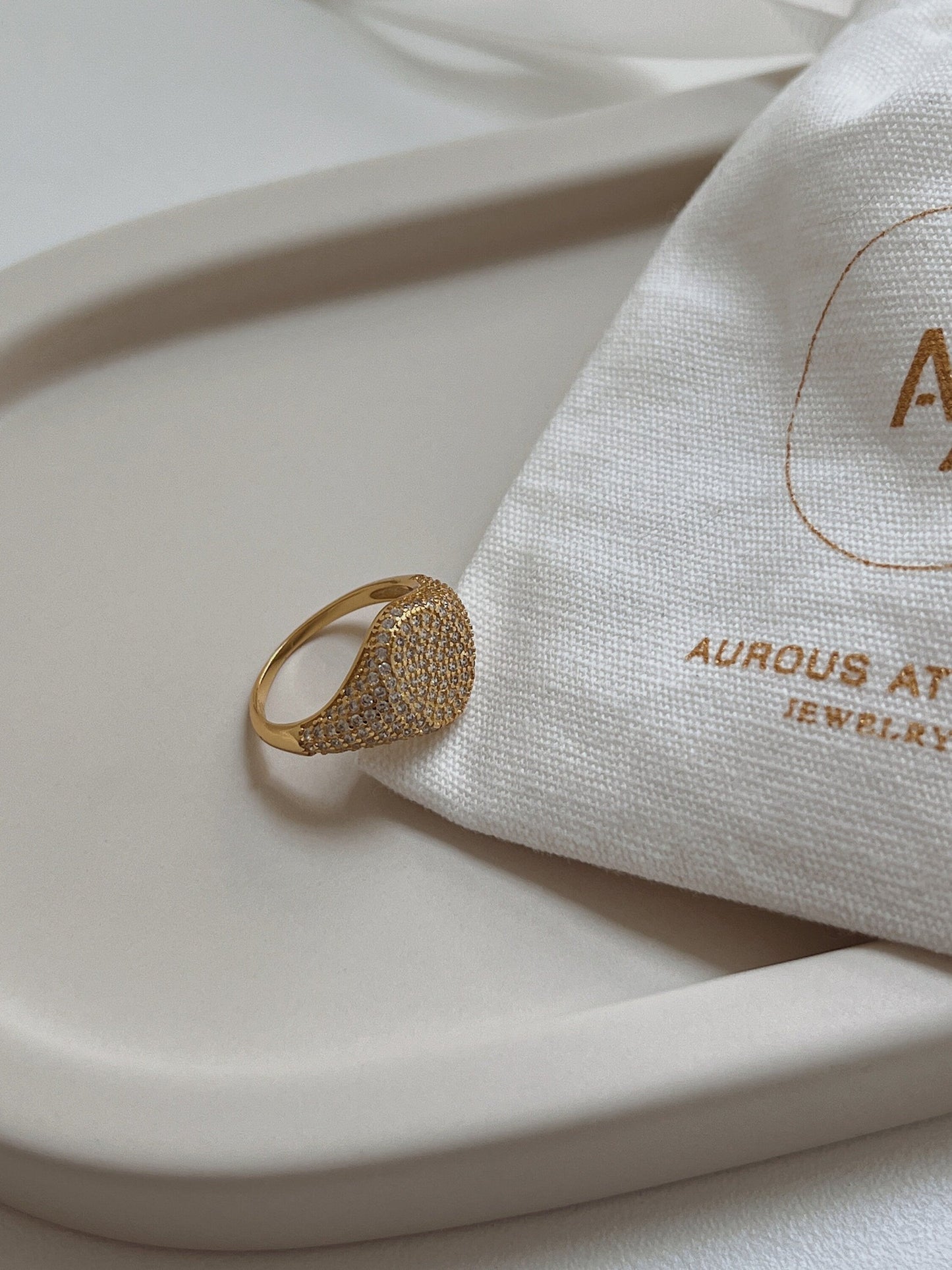 Lightweight gold signet ring resting on a minimalist jewelry tray.