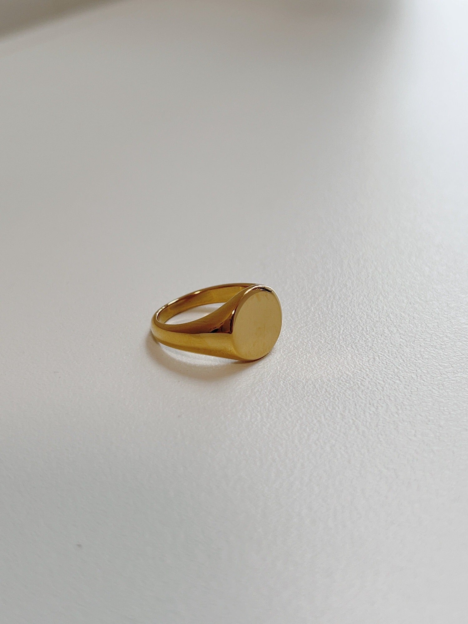 Close up of tapered gold signet ring highlighting the flat face