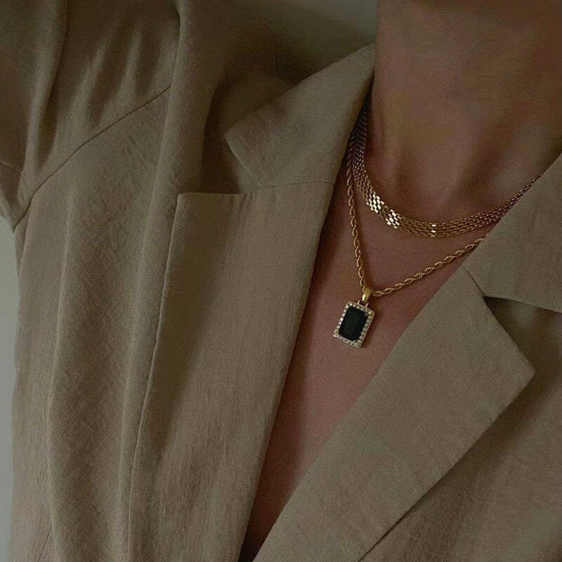 Front lifestyle view of an 8mm gold woven collar chain resting flat against a clean minimalist neckline