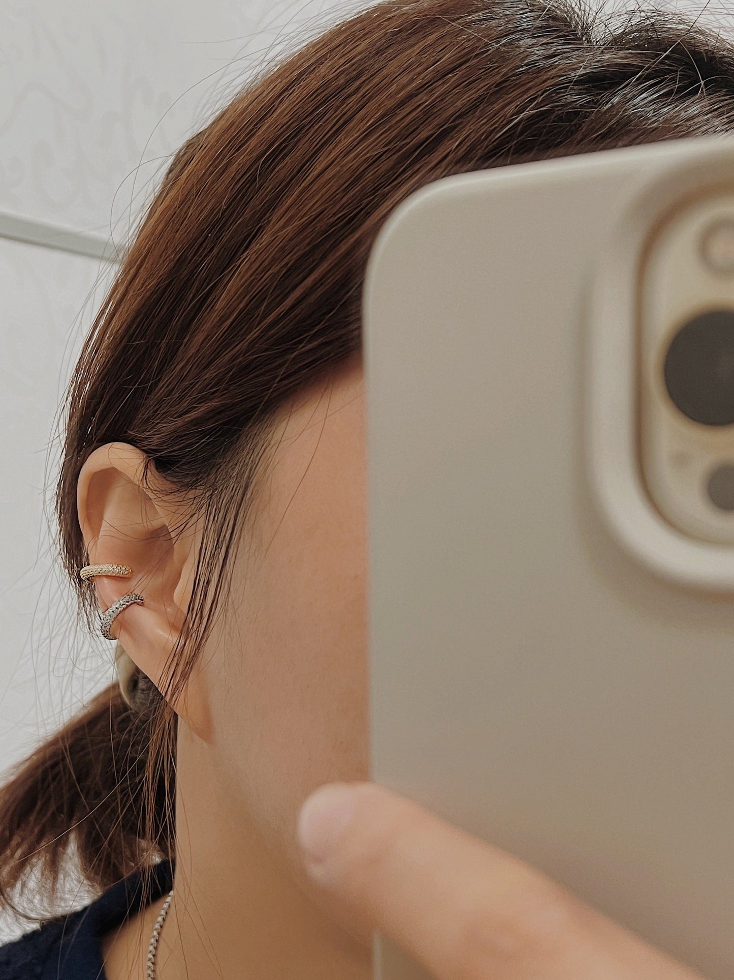 A natural lifestyle shot of a model wearing the Rose Ear Cuff, demonstrating how the triple-row crystals catch the light during movement.