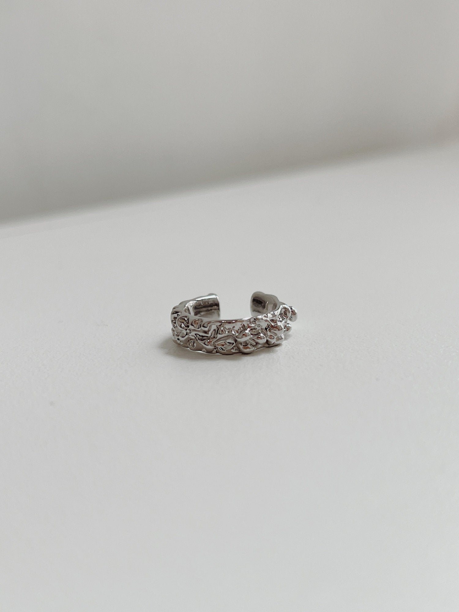 Detail view showing the architectural, wide-band silhouette of the Silver Molten Ridge ear cuff.