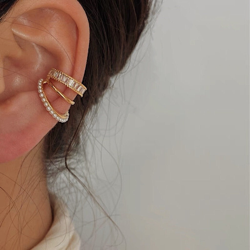 Fashion-forward ear stack with pearls and gold cuffs on model.