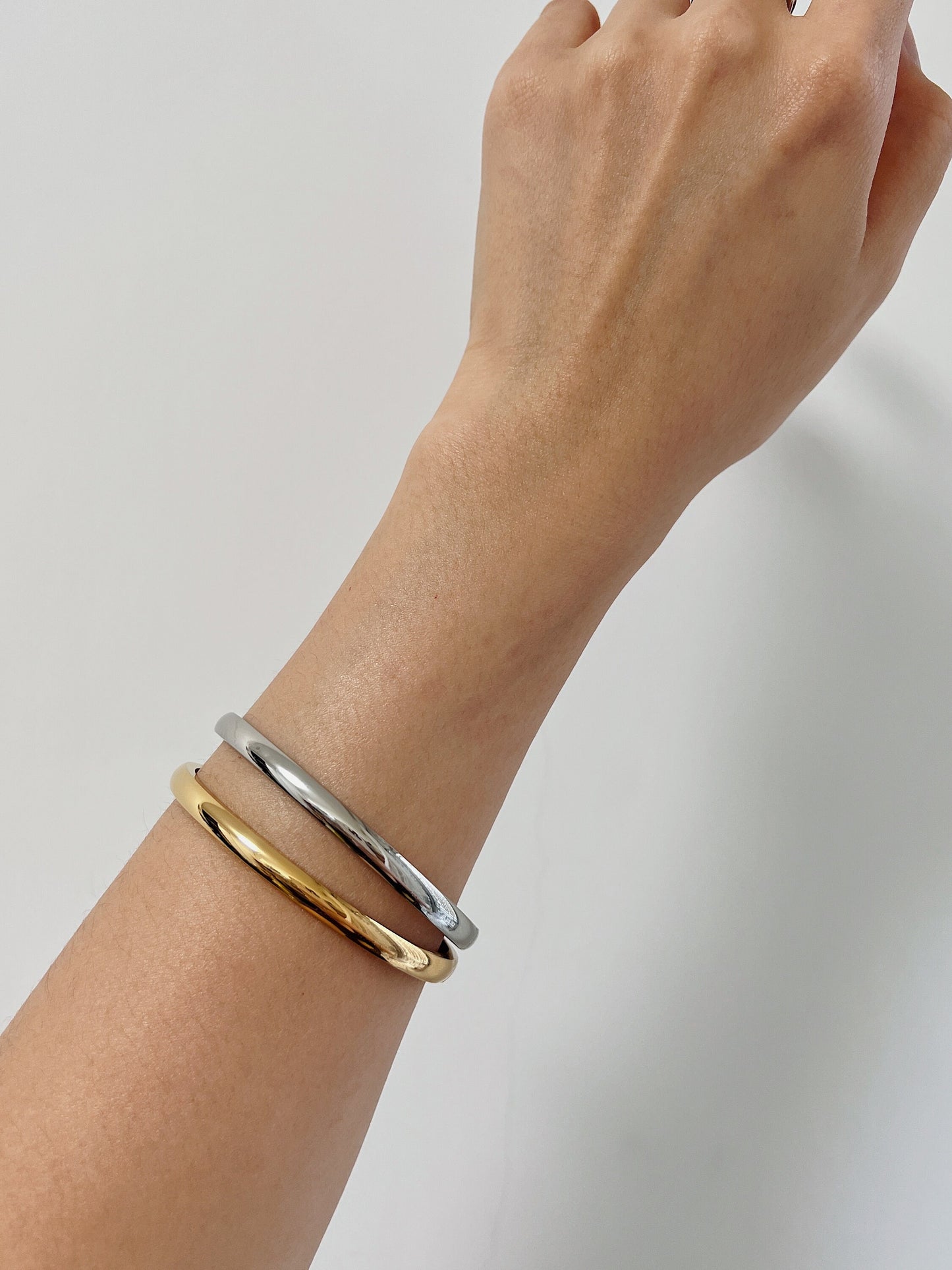 Close-up model shot showcasing how the 18K gold Jayden oval bangle contours comfortably to the wrist.