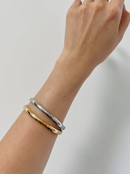 Close-up model shot showcasing how the 18K gold Jayden oval bangle contours comfortably to the wrist.