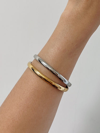 Model wrist wearing the Jayden 18K gold and silver oval bangles stacked together for a modern mixed-metal look.