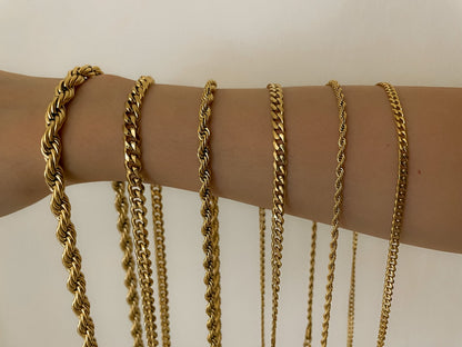 A comparative row of diverse gold chains draped vertically across an arm showcasing variations of a thick helical rope, structured curb link, and fine paperclip necklace