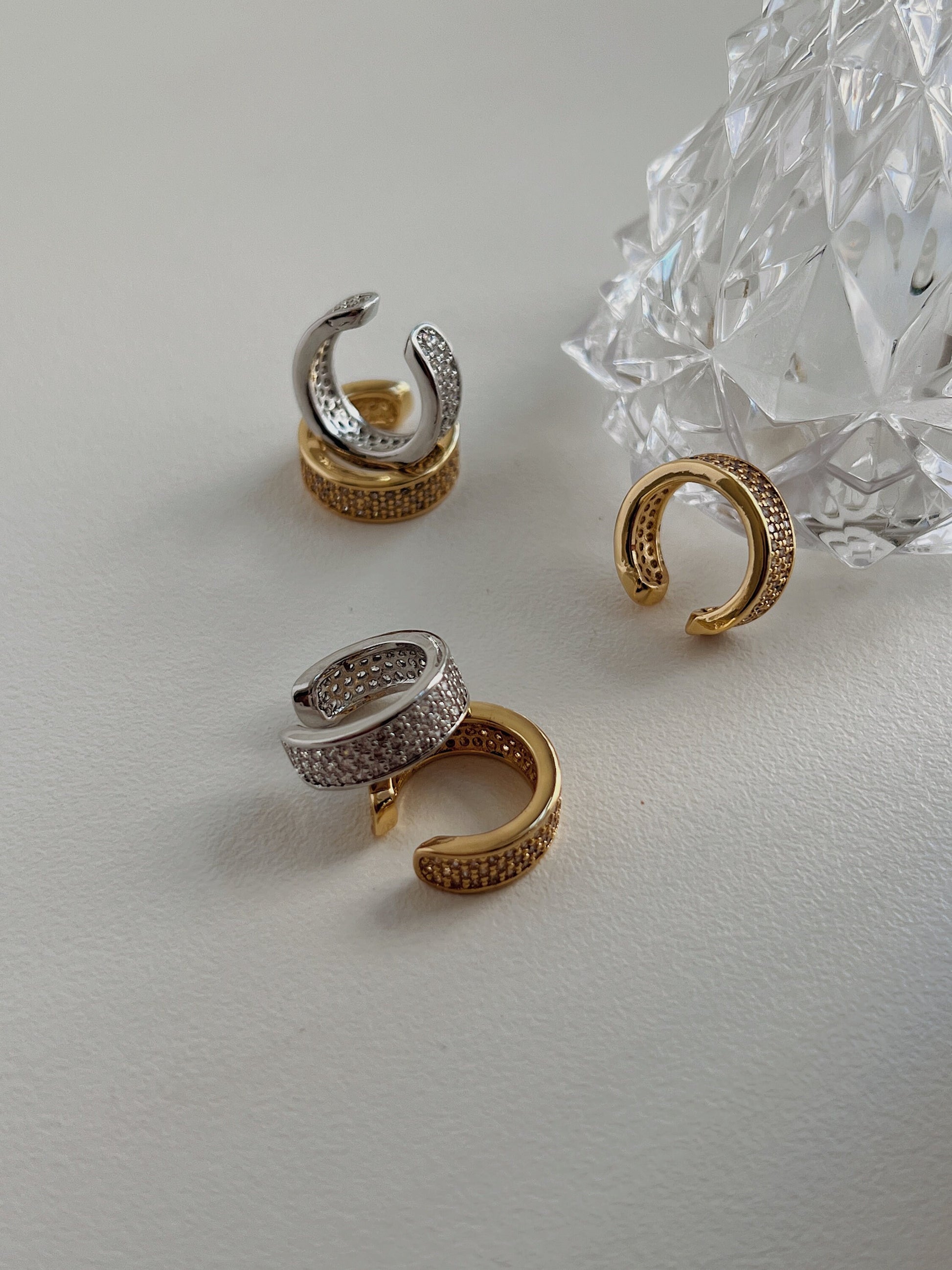 High-shine CZ pave detailing on thick gold and silver ear cuff.